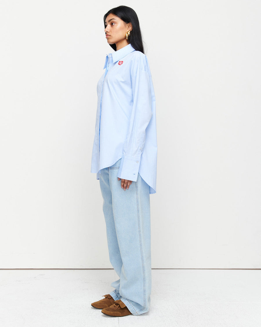 The Classic Cotton Shirt is an oversized essential, crafted from 100% cotton for effortless wear. Featuring a cheeky kiss embroidery under the left collar, this piece showcases exclusive artwork in collaboration with Anouk Colantoni.