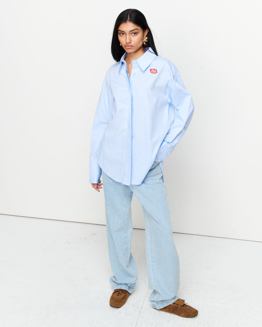 The Classic Cotton Shirt is an oversized essential, crafted from 100% cotton for effortless wear. Featuring a cheeky kiss embroidery under the left collar, this piece showcases exclusive artwork in collaboration with Anouk Colantoni.