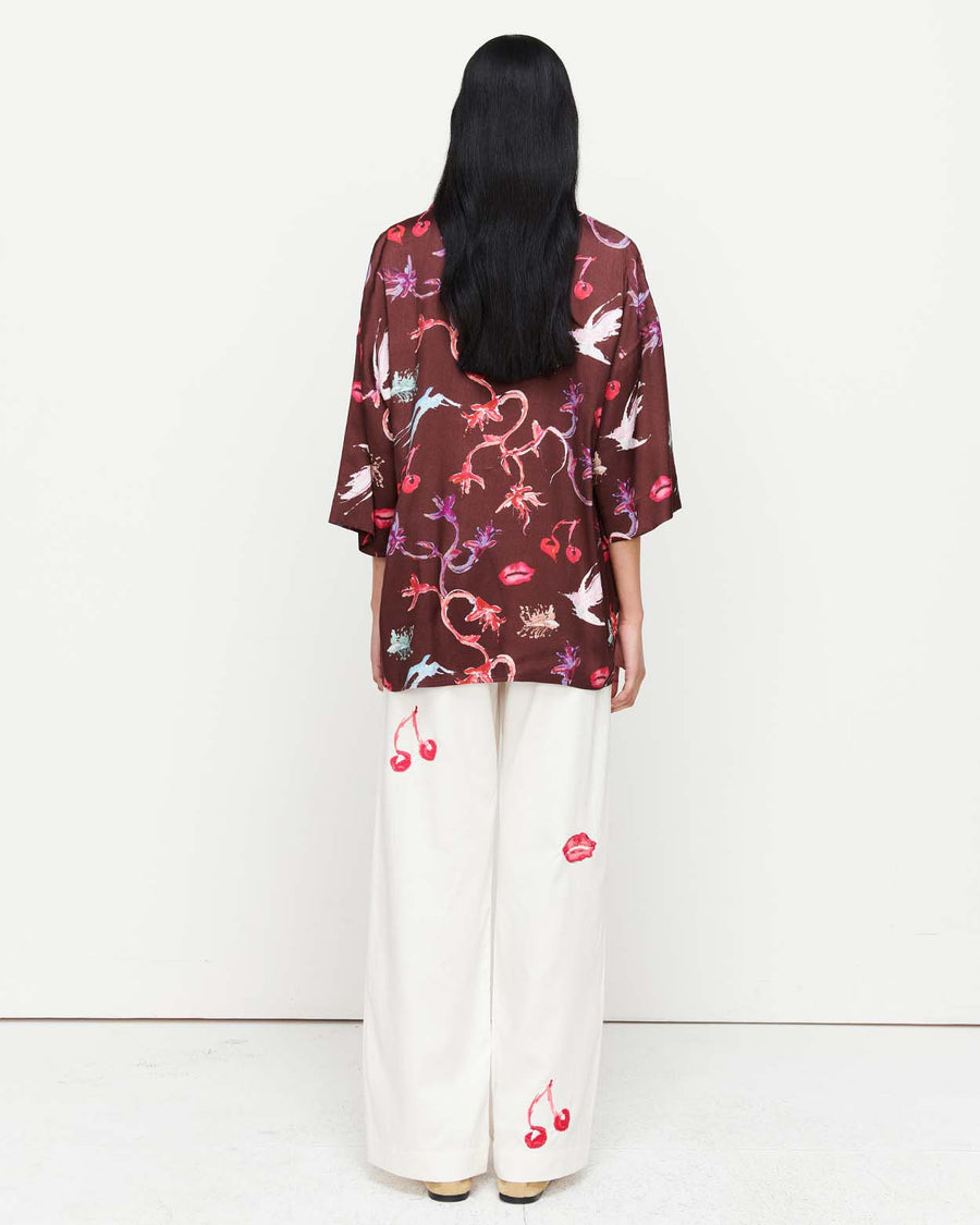 Effortlessly chic, the June Shirt features an oversized fit with short sleeves, a concealed placket, and exaggerated sleeves. Adorned with exclusive artwork in collaboration with Anouk Colantoni.