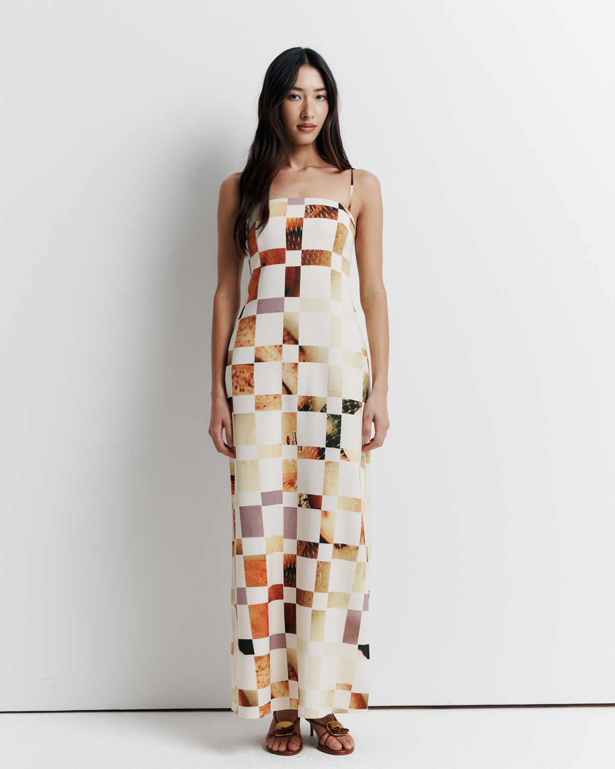 Model in a column dress with straight neckline, rouleau straps, invisible back zip, internal bustier with boning, checkerboard artwork by Phoebe Willis.