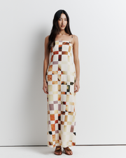 Model in a column dress with straight neckline, rouleau straps, invisible back zip, internal bustier with boning, checkerboard artwork by Phoebe Willis.
