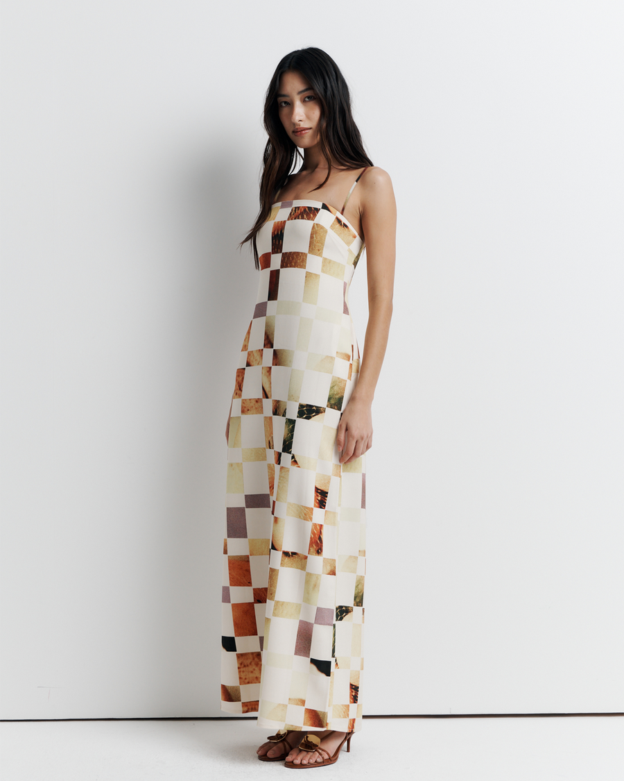 Model in a column dress with straight neckline, rouleau straps, invisible back zip, internal bustier with boning, checkerboard artwork by Phoebe Willis.