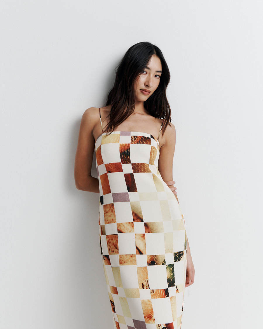 Model in a column dress with straight neckline, rouleau straps, invisible back zip, internal bustier with boning, checkerboard artwork by Phoebe Willis.