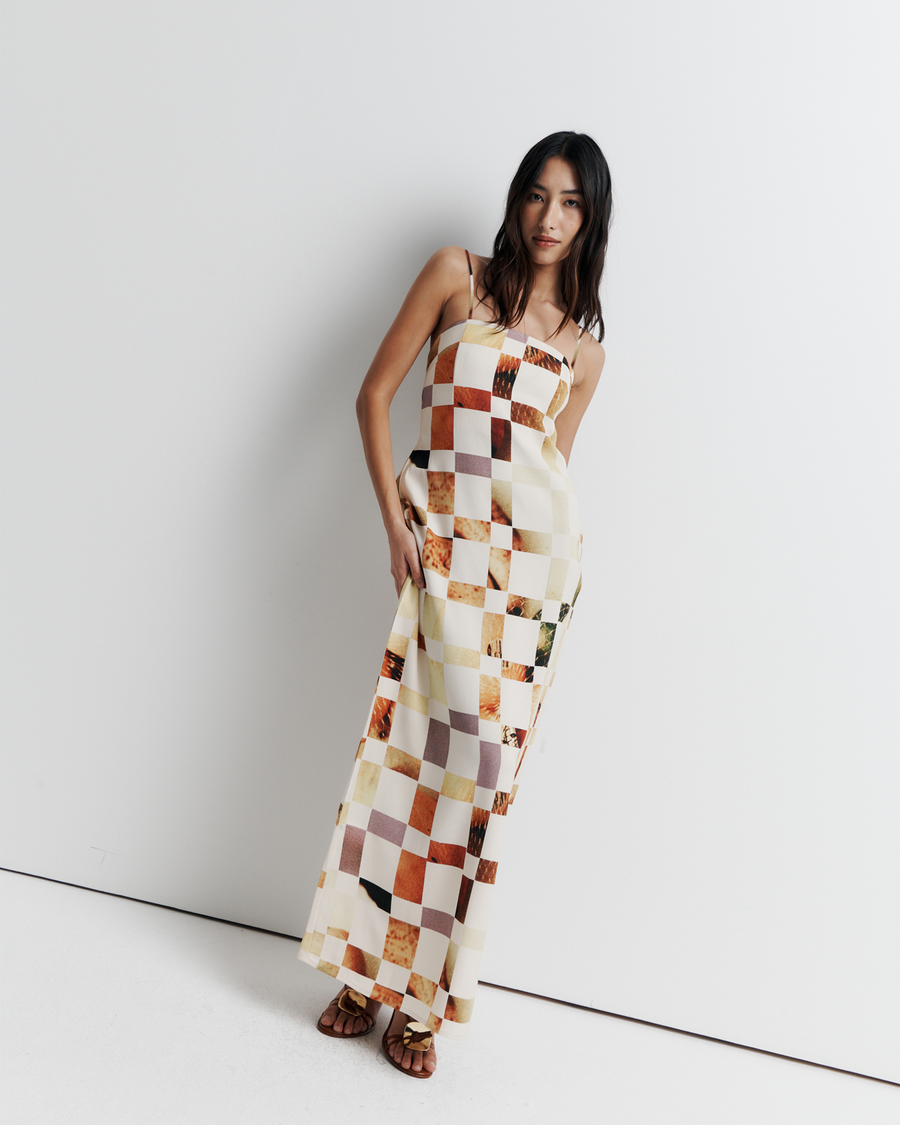 Model in a column dress with straight neckline, rouleau straps, invisible back zip, internal bustier with boning, checkerboard artwork by Phoebe Willis.