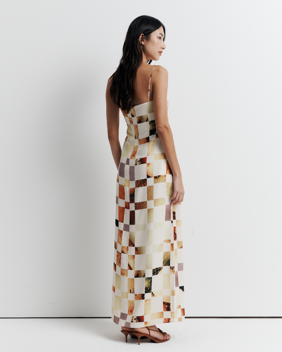 Model in a column dress with straight neckline, rouleau straps, invisible back zip, internal bustier with boning, checkerboard artwork by Phoebe Willis.
