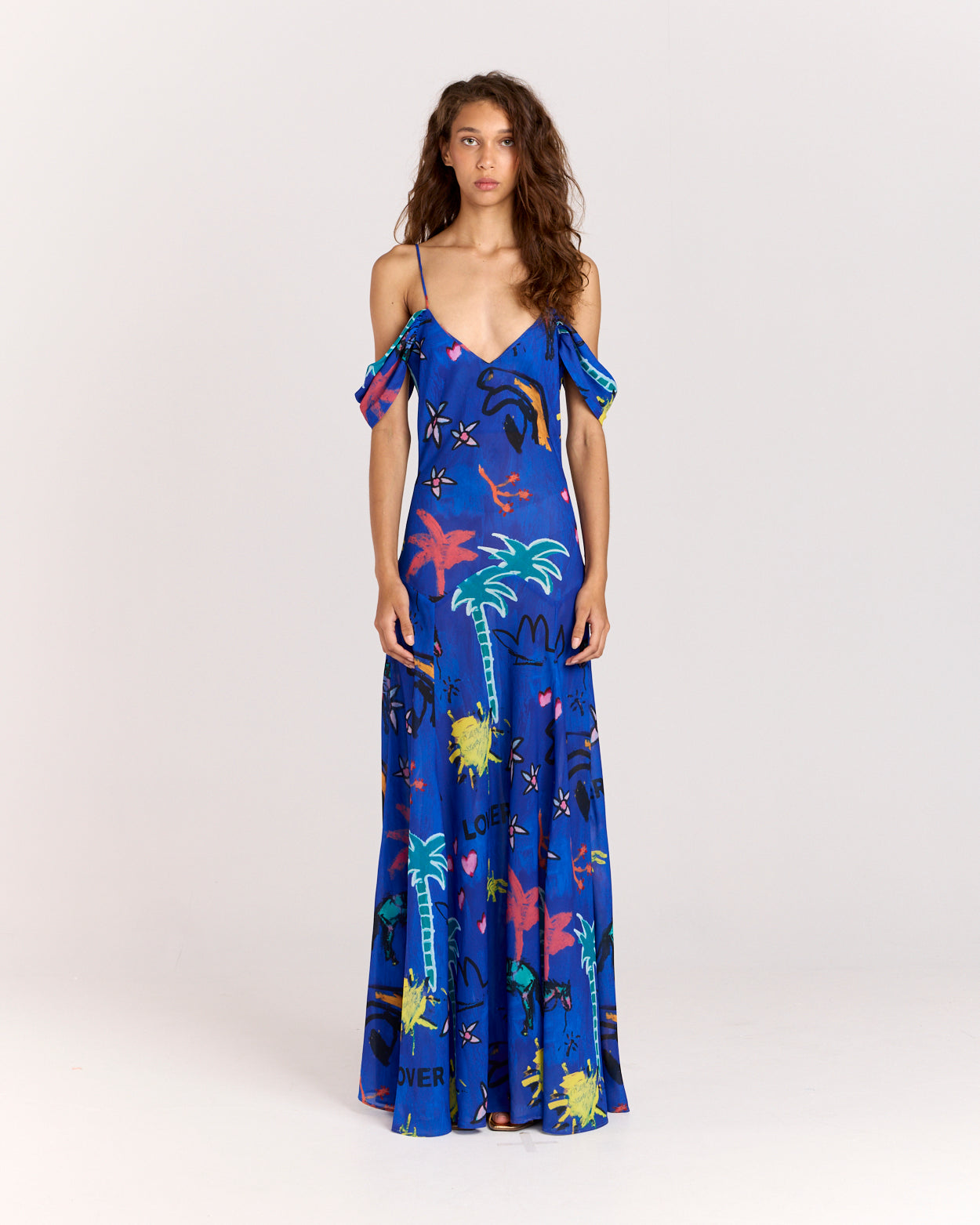Make a bold statement with the Lover Gown, featuring Jake Pedro's exclusive Lover Print in a striking blue hue. Designed with a drop waist, adjustable straps, and a voluminous floor-length skirt, this gown offers elegance with a touch of sheerness.